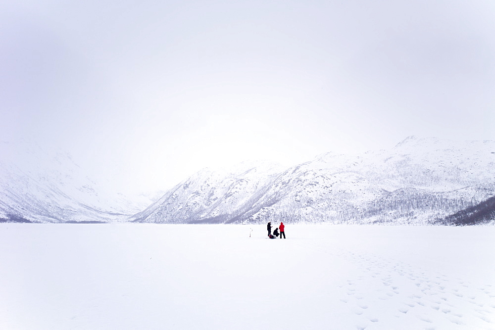 Ice fishing on frozen lake in the arctic alps in the Arctic Circle on Ringvassoya Island in the region of Tromso, Northern Norway