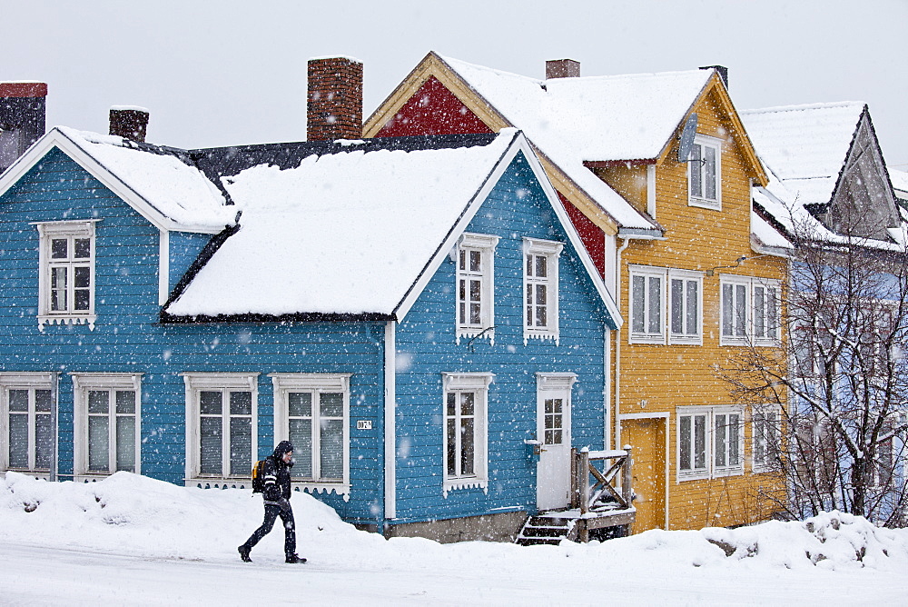 Man walks past traditional wooden buildings along Storgata in the quaint area of Tromso, in the Arctic Circle in Northern Norway