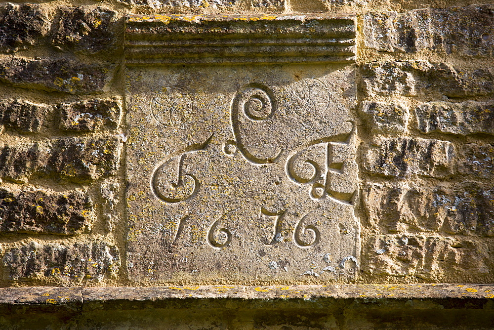 Date 1676 of traditional 17th Century cottage of old Cotswold stone at Taynton in The Cotswolds, Gloucestershire, UK