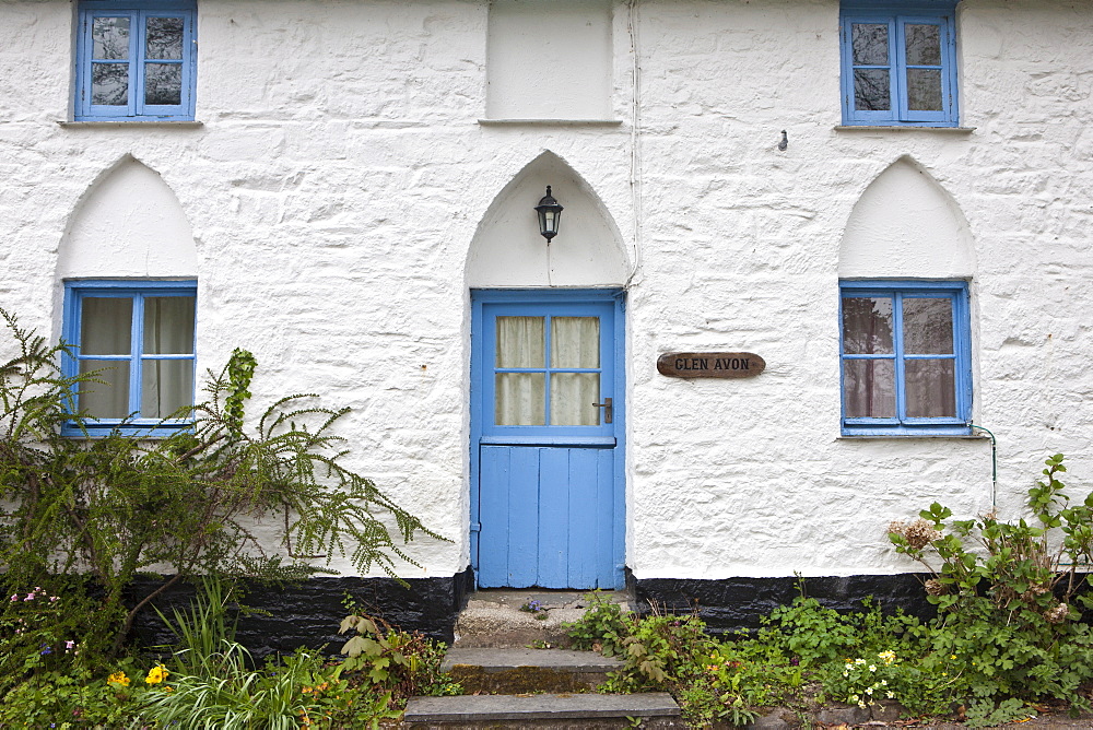 Quaint brightly-painted traditional cottage with gothic style arched door , Cornwall, England, UK