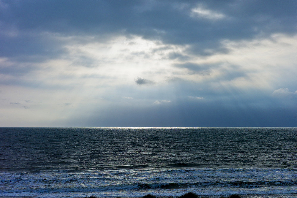 Sun's rays over rough sea at dawn on a windy day at Rosslare, South East Ireland