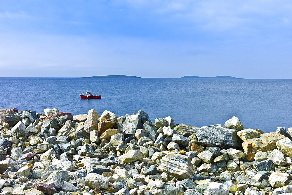 Fishing boat with Saltee Islands in background and sea defences, Kilmore, County Wexford, Ireland