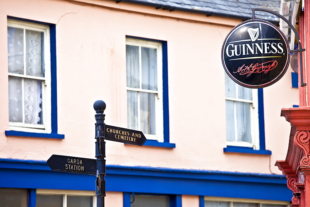 Signpost to Garda, Churches and Cemetery next to Guinness advertisement at bar in Timoleague, West Cork, Ireland