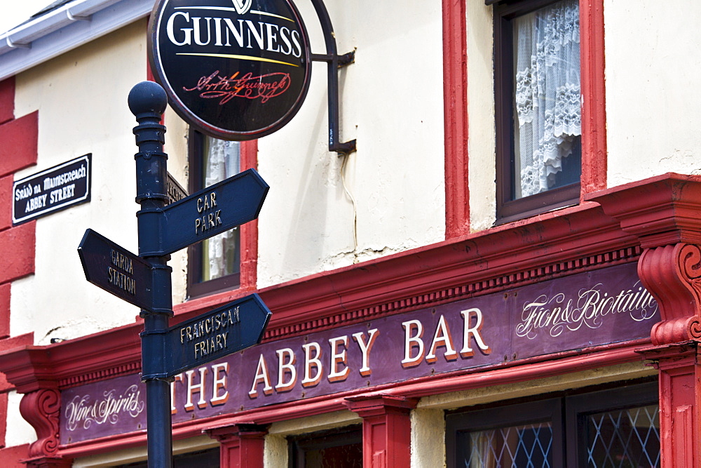 Signpost to Garda and Car park next to Guinness advertisement at The Abbey Bar in Abbey Street, Timoleague, West Cork, Ireland