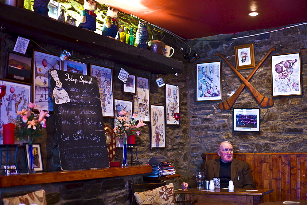 Elderly man sits alone with cup of tea and beer in traditional Irish Bar Grainne's in Timoleague, West Cork, Ireland