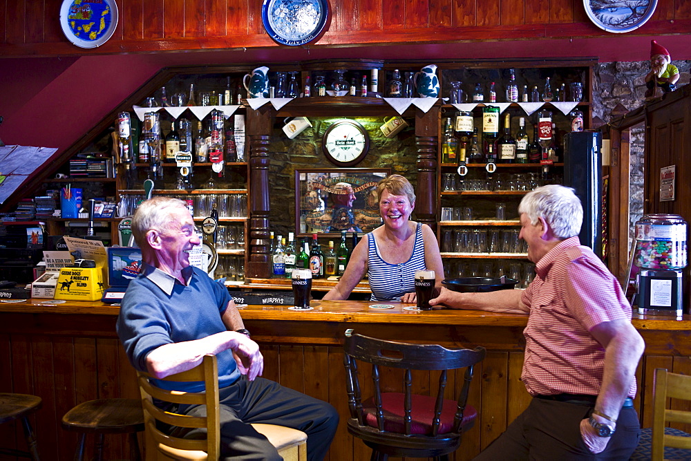 Grainne laughing with locals at her traditional Irish bar, Grainne's, in Mill Street, Timoleague, West Cork, Ireland