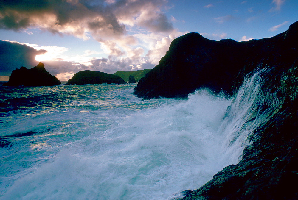 Waves breaking against the cliffs making sea spray at Kinance Cove, Cornwall, England, United Kingdom