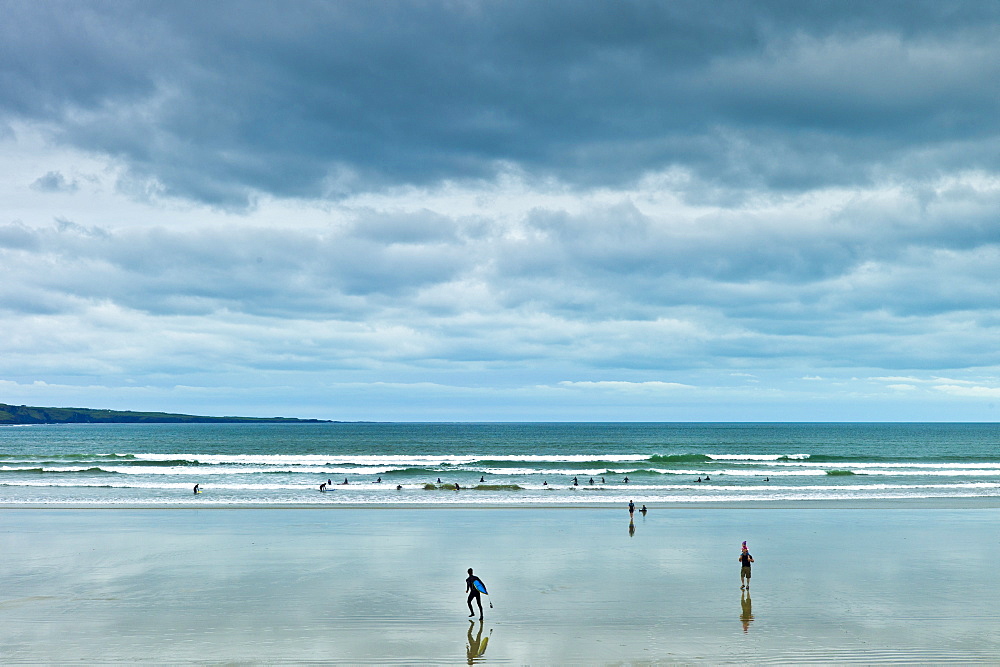 Waves, tide  and surfers with surfboards at Lahinch, Lehinch,  famous surfing beach, County Clare, West Coast of Ireland