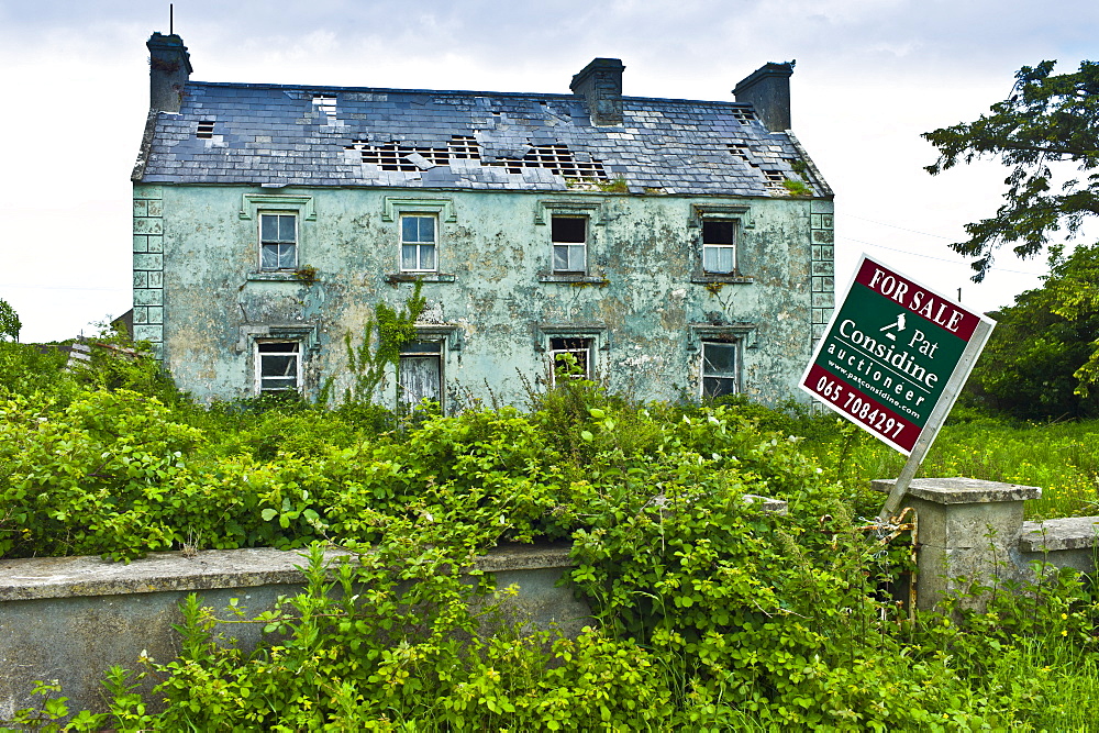 Derelict period house  with for sale estate agent auctioneer board in Moyasta, County Clare, West of Ireland