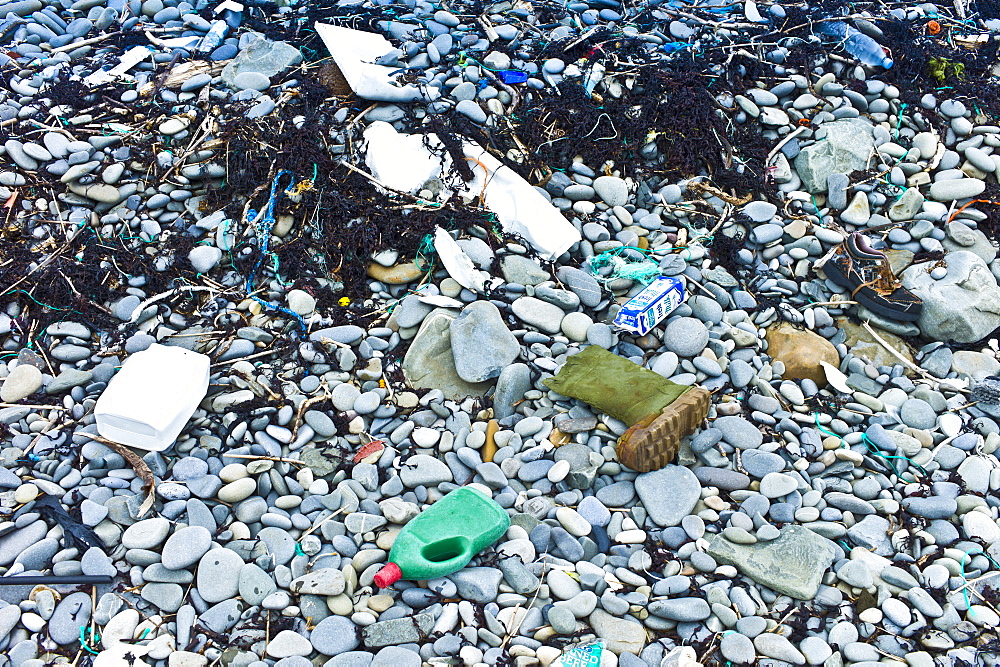 Detritis debris of plastic, and polluting plasticized materials swept in from the sea litter rocks on beach in West Coast of Ireland