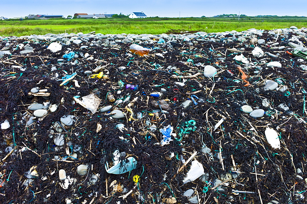 Detritis debris of plastic, and polluting plasticized materials swept in from the sea litter rocks on beach in West Coast of Ireland