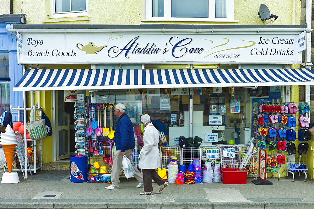 Retired couple pass Aladdin's Cave store selling seaside products in Aberdyfi, Aberdovey, Snowdonia, Wales