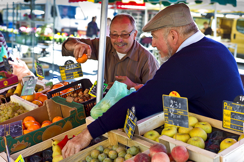 Frenchmen working  on fruit staff at food market at Esplanade  des Quais in La Reole, Bordeaux region, France