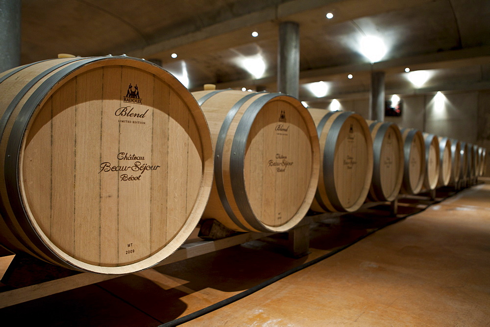 Oak wine barrels in cave at Chateau Beau-Sejour Becot at St Emilion in the Bordeaux wine region of France