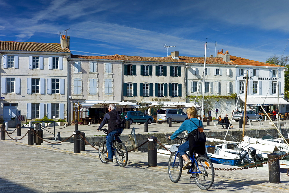 Tourists cycling along the harbour at Quai de Senac in La Flotte, Ile de Re, France