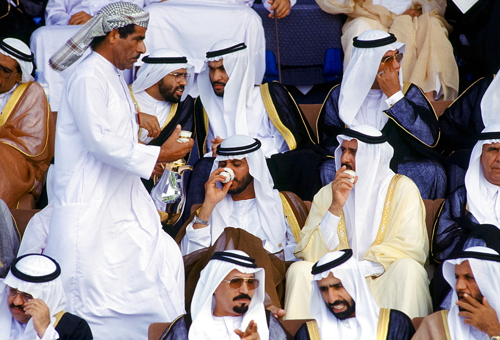 Arab sheikhs drinking coffee and watching parade of armed forces in Abu Dhabi, United Arab Emirates