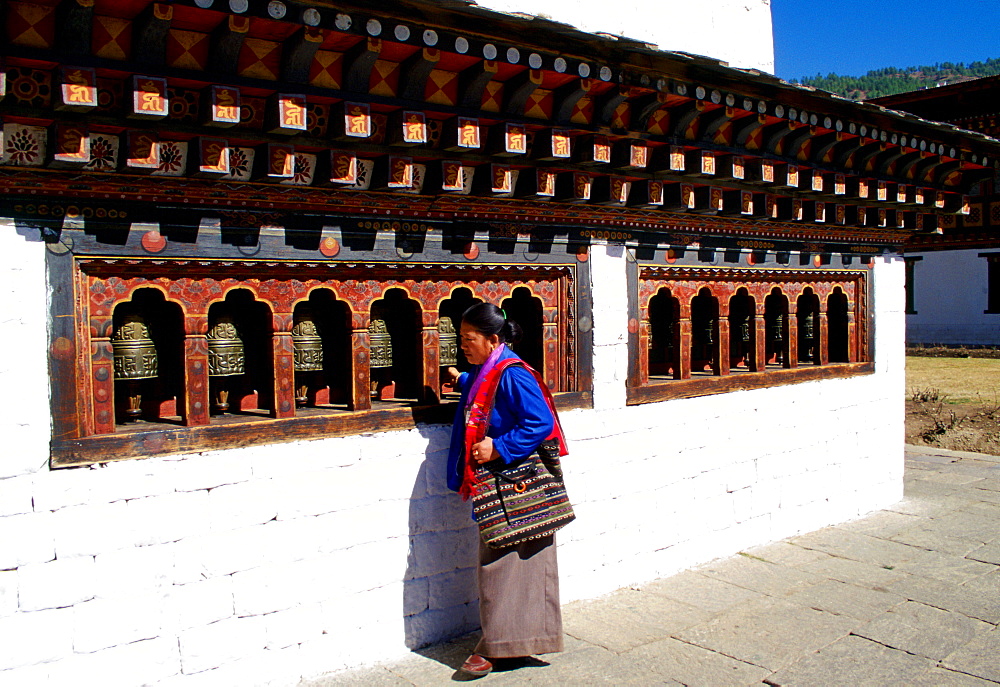 A native woman saying prayers and using a prayer wheel at Tashichho Dzong in Thimpu