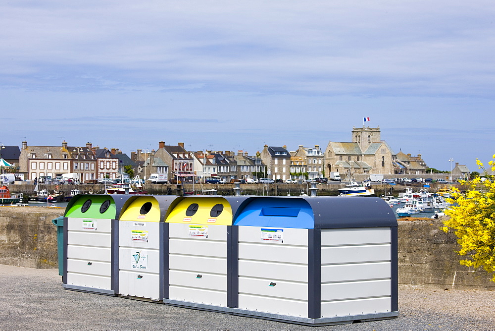 Large plastic recycling bins, dechetterie, for plastic, paper, glass spoil the view in Barfleur in Normandy, France