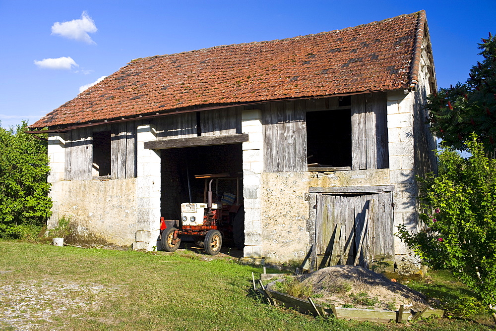 Old farmyard tractor in a barn at Boulouneix near Brantome, France