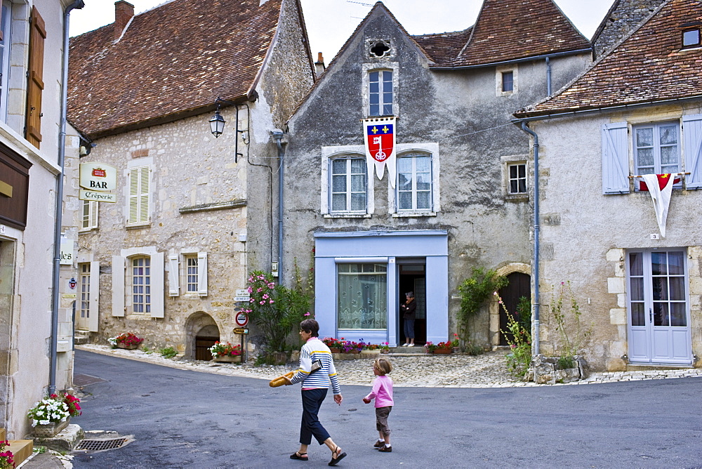 Woman carrying French baguette bread stick walks with child at Angles Sur L'Anglin, Vienne, Poitou-Charantes, France