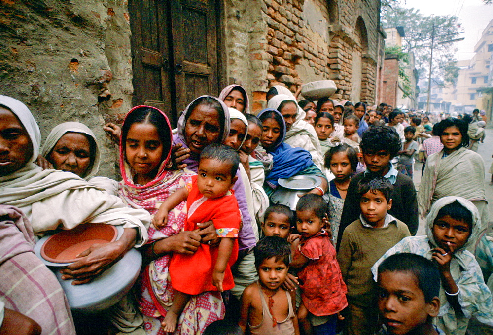 Women carrying pots with children in early morning food queue at Mother Teresa's Mission Calcutta, India