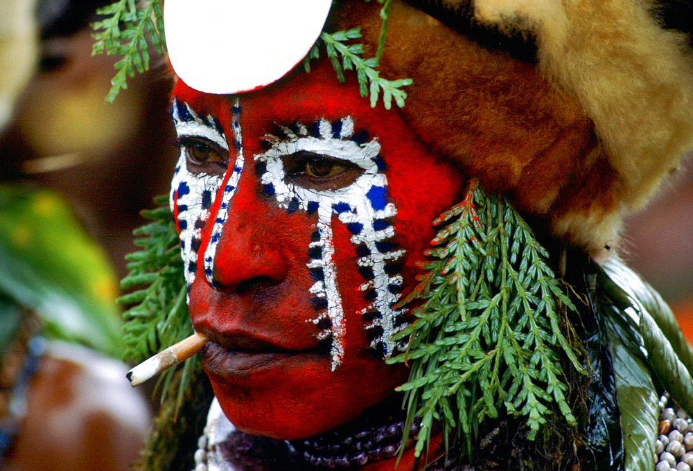 Tribesman with painted face and a cigarette in Papua New Guinea