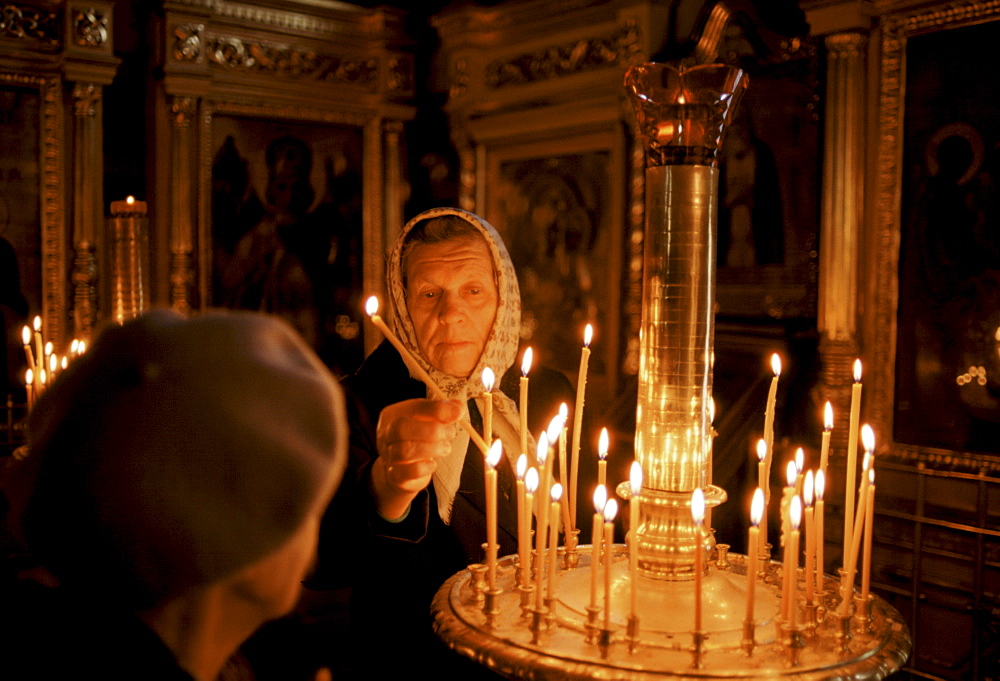 Russian Orthodox worshipper  lighting candles in church in Zagorsk, near Moscow, Russia