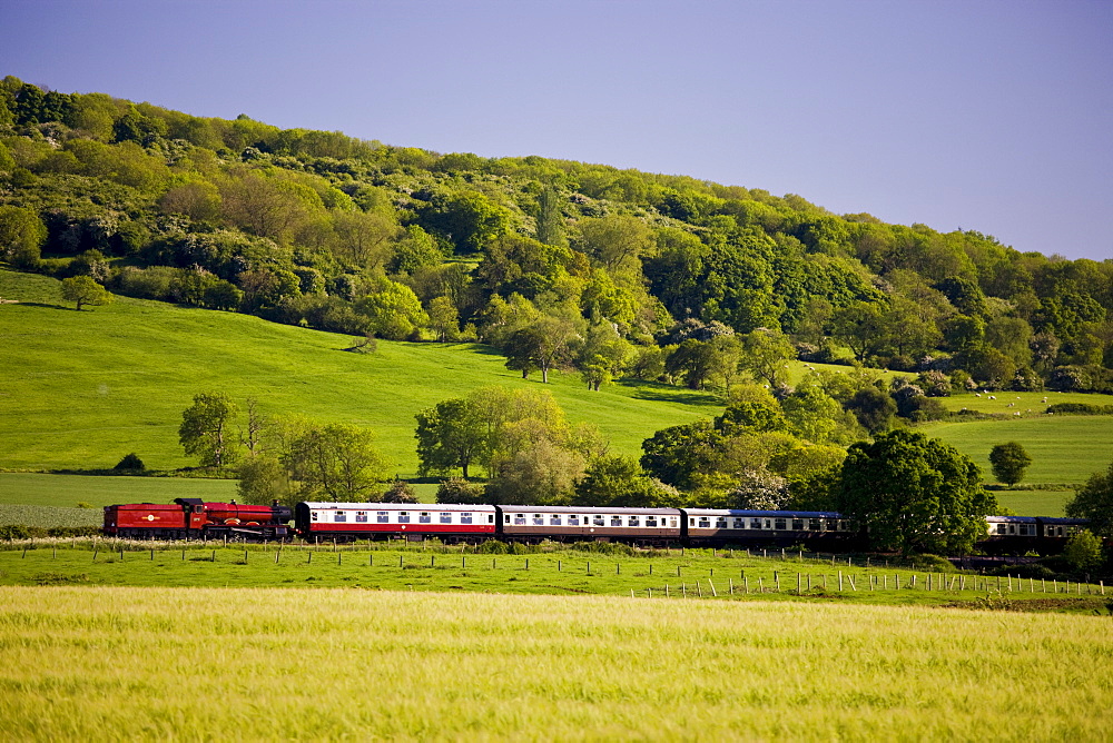 Traditional old steam engine locomotive train with carriages in Cotswolds countryside near Winchcombe in Gloucestershire