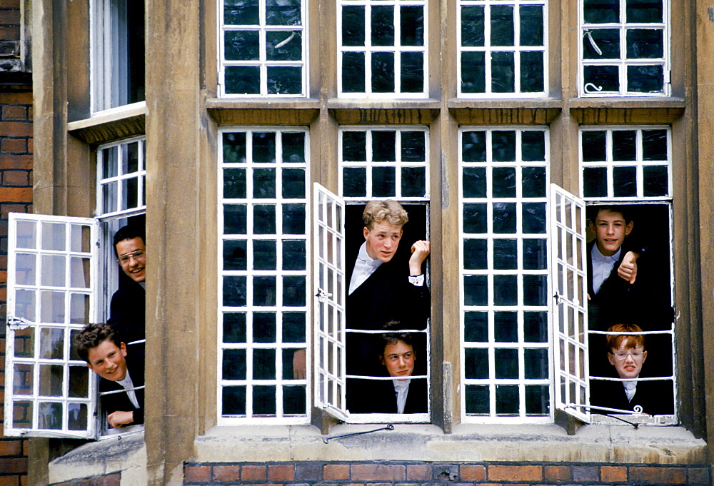 Eton schoolboys in traditional tails looking through the window at Eton College, England, UK