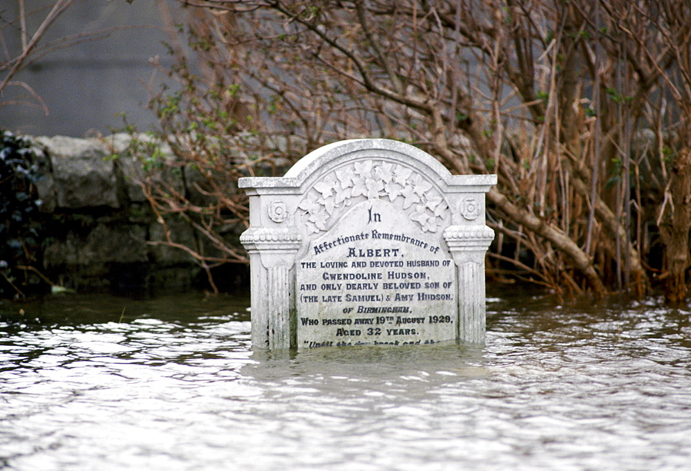 Deep flooding nearly covers gravestone in Towyn in North Wales, UK