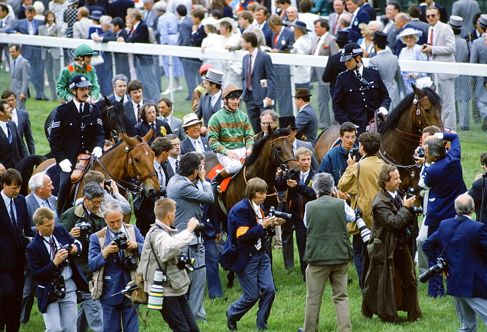 Press photographers and reporters surround the winning horse and jockey at Epsom Racecourse on Derby Day, UK