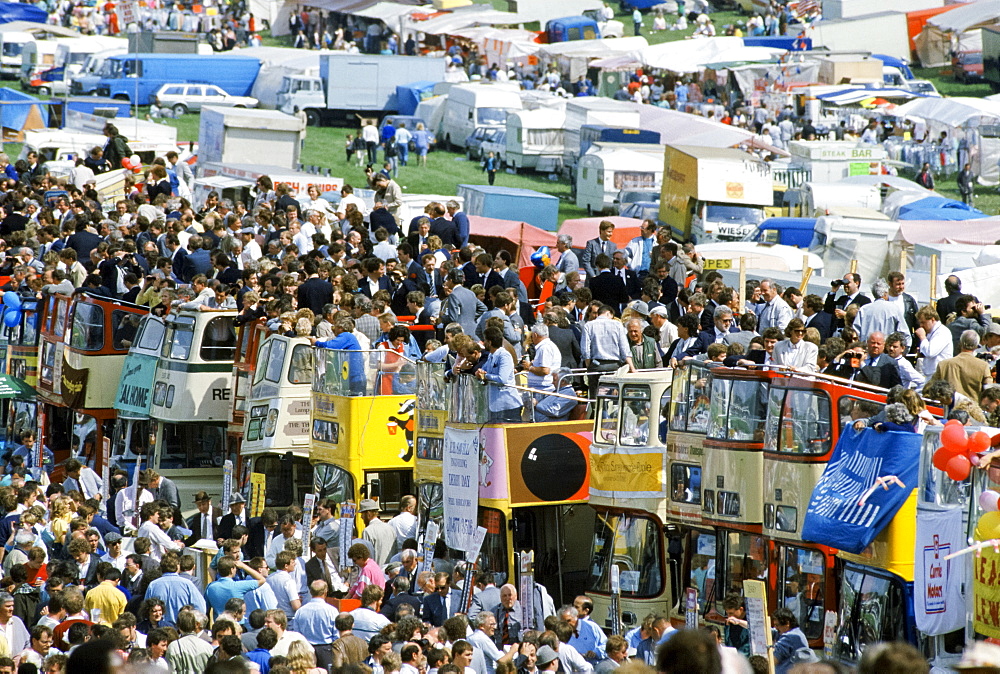 Crowds of spectactors on traditional open-topped buses in The Hill public area at Epsom Racecourse for Derby Day, UK