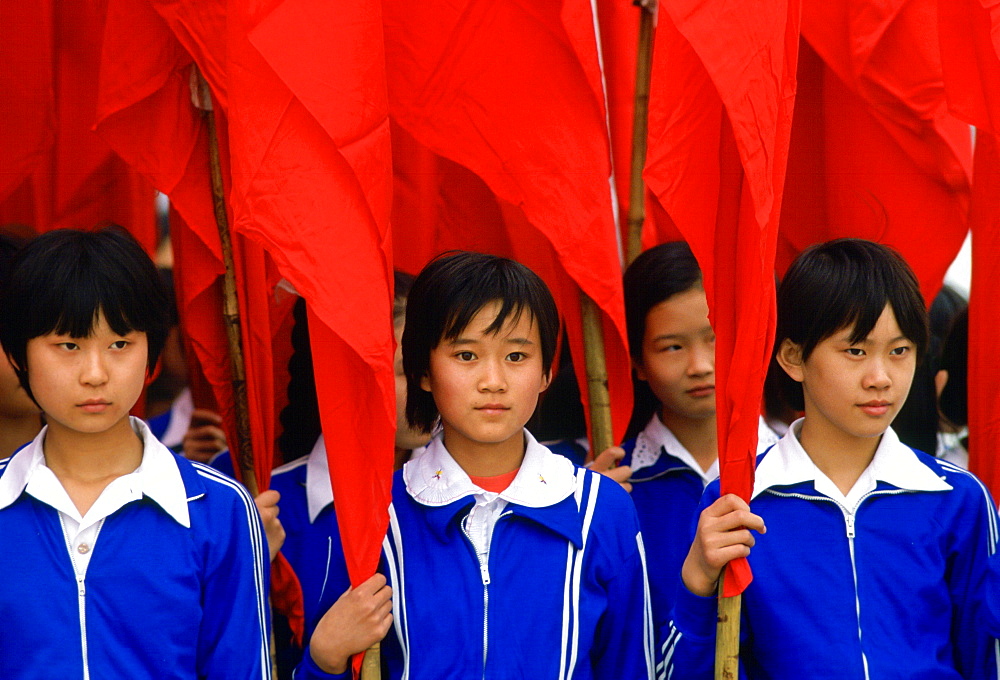 Schoolgirls wearing school uniforms and holding  traditional red flags in Xian, China