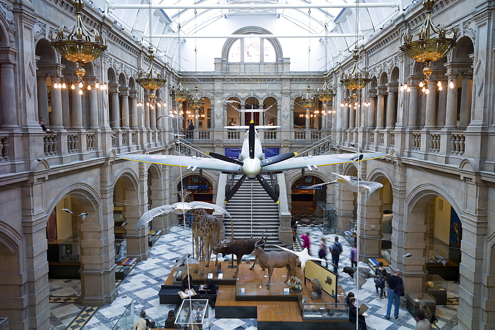 Visitors at Kelvingrove Art Gallery and Museum with suspended Spitfire World War II airplane exhibit on display in the West Court in Glasgow, Scotland, United Kingdom, Europe