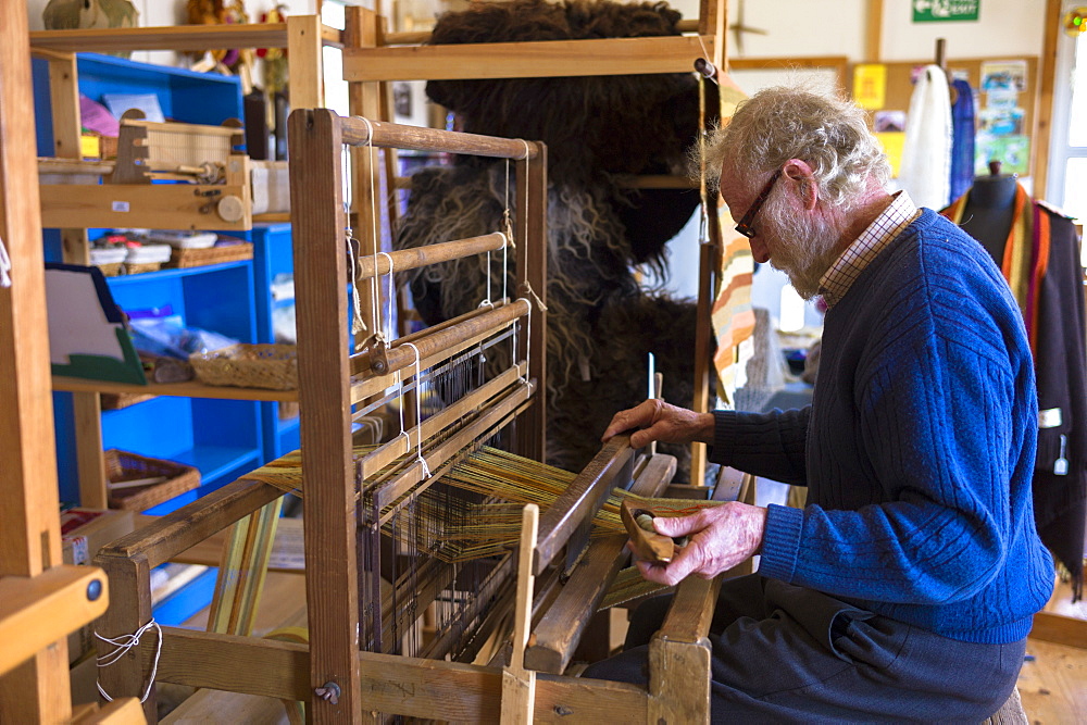 Craftsman using traditional loom to weave wool into handmade scarf at Croft Wools and Weavers, Applecross in the Highlands of Scotland, United Kingdom, Europe