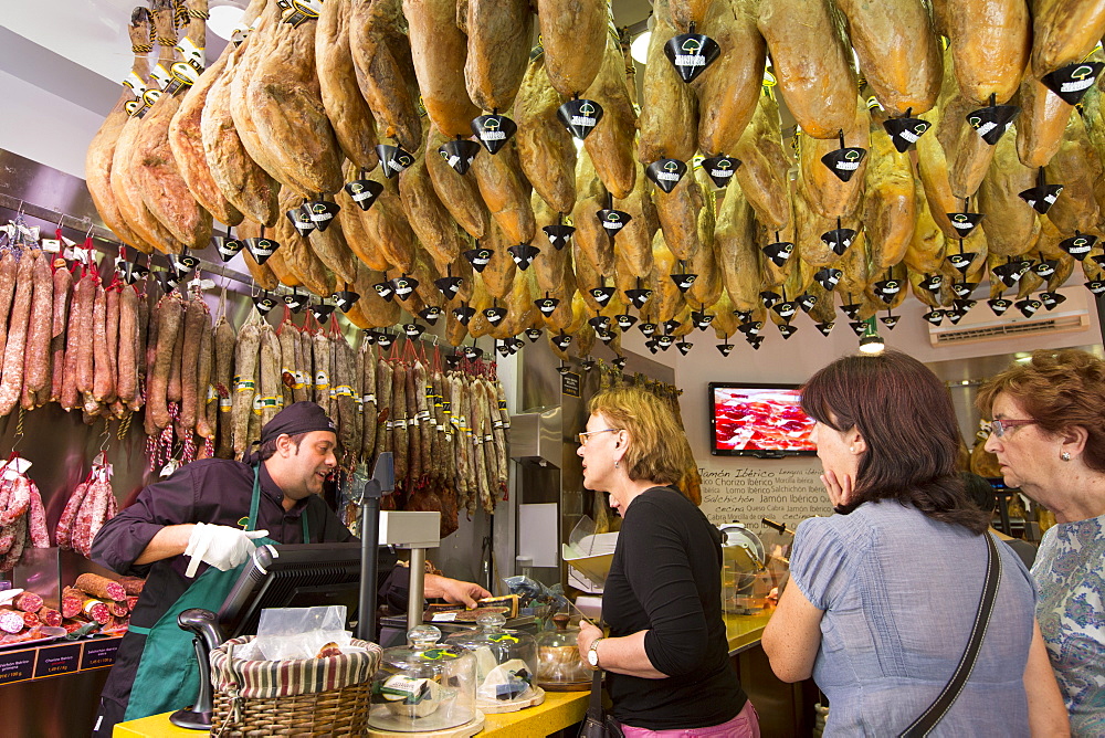 Shoppers in butcher's shop to buy Iberico Jamon Ham and other meats in Calle de Bidebarrieta in Bilbao, Euskadi, Spain, Europe