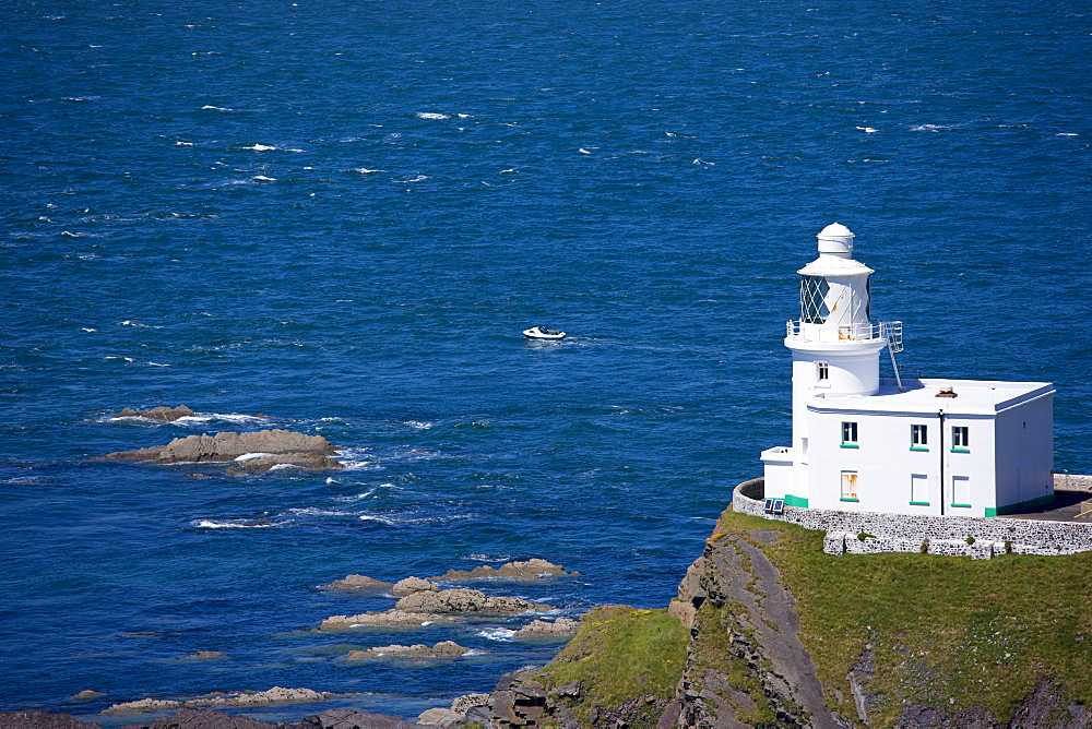 Speedboat passes Hartland Point Lighthouse, 19th Century Grade II listed, Atlantic Ocean and Bristol Channel in North West Devon, Devon, England, United Kingdom, Europe