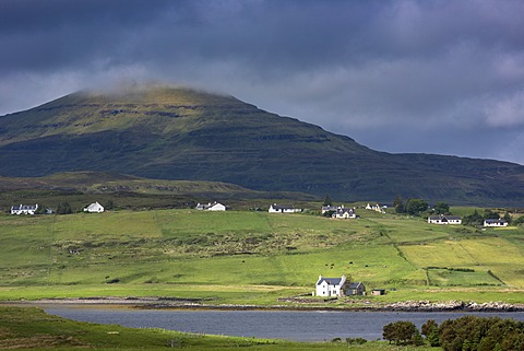 White croft cottages nestled in hamlet by mountain and Loch Vatten under grey clouds at Roag, Isle of Skye, Inner Hebrides and Western Isles, Scotland, United Kingdom, Europe