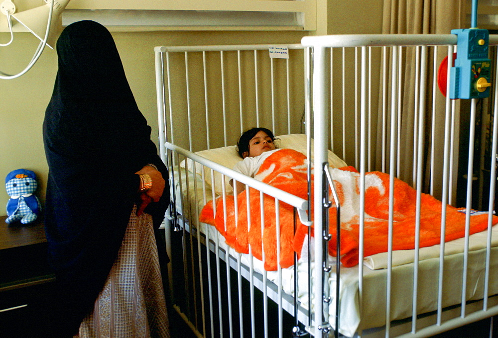 A Saudi mother stays with her child who is in a hospital cot at Moda Hospital in Riyadh, Saudi Arabia