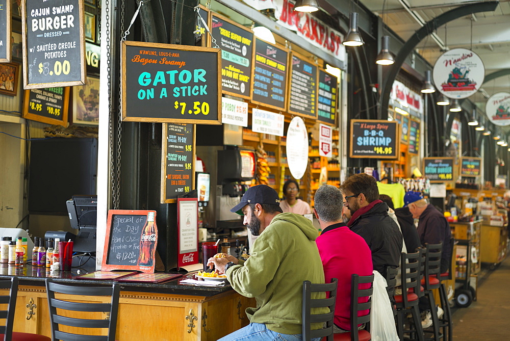 Diners at cafe bar in French Market food market, Decatur Street, French Quarter, New Orleans, USA. Gator on a stick a specialty