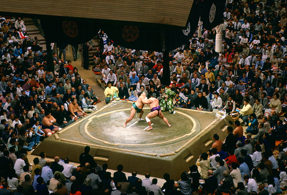 Sumo wrestlers in the ring watched by a big crowd  in Tokyo, Japan