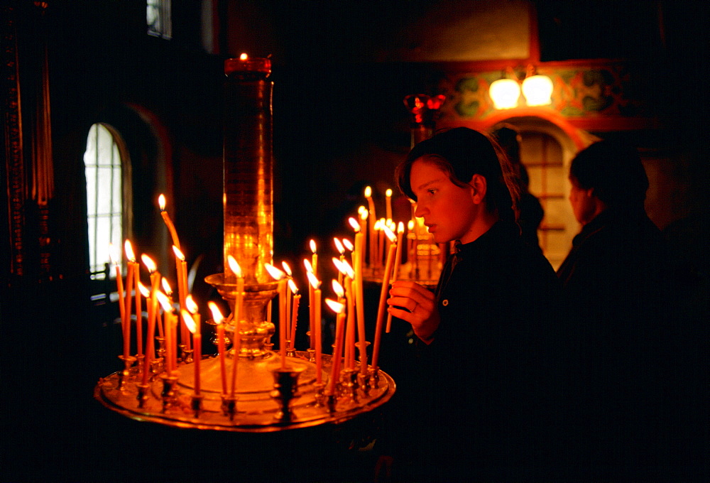 Woman worshipper holding a lighted candle in a church in Zagorsk, Russia