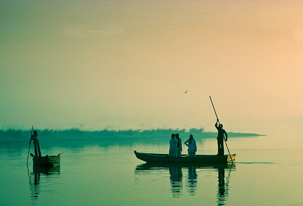 Man ferries passengers in a small boat, India