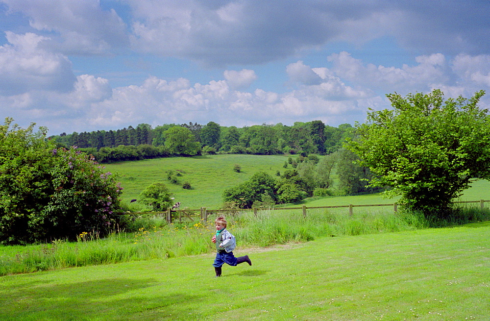 A four year old boy running across a field in Wiltshire, England