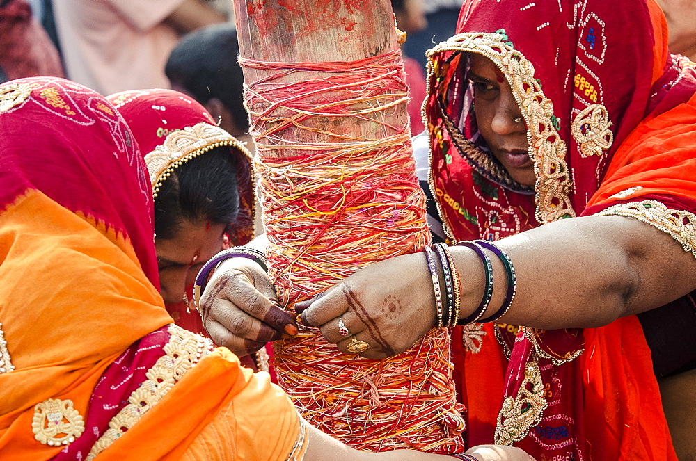 Women apply string to the Holi chir, a traditional morning ceremony, during Holi festival celebrations, Basantapur Durbar Square, Kathmandu, Nepal, Asia 