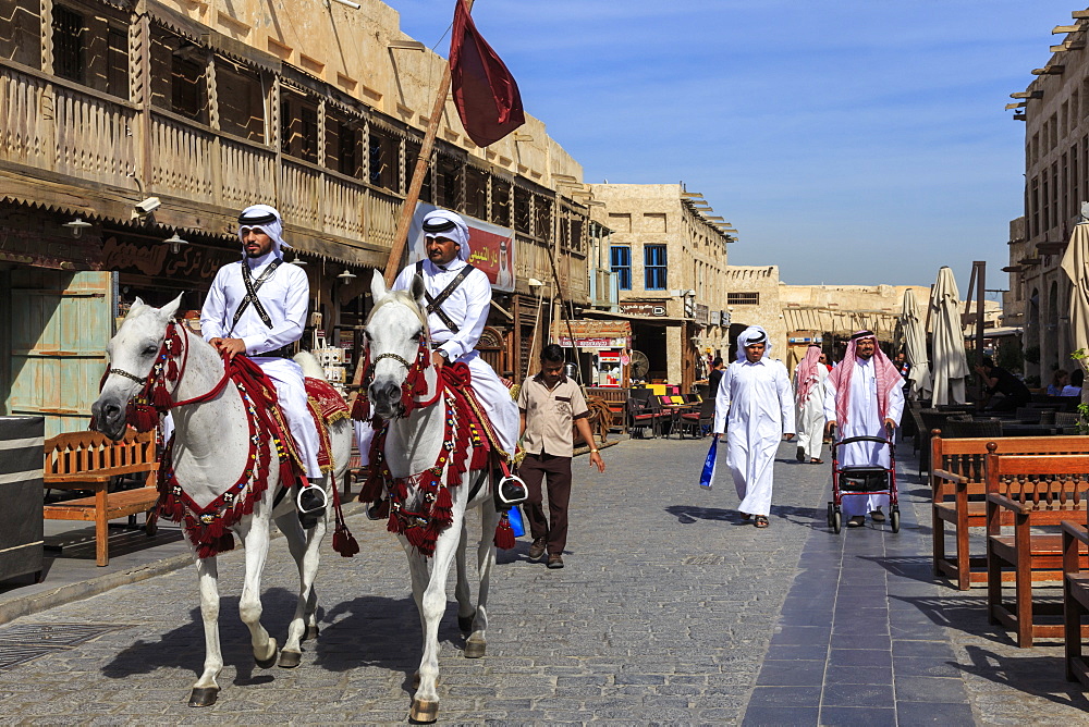 Busy street scene with traditionally dressed mounted policemen and shoppers, Souq Waqif, Doha, Qatar, Middle East