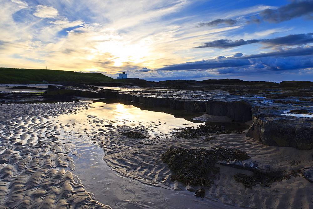 Summer sunset over Bamburgh beach lighthouse, Bamburgh, Northumberland, England