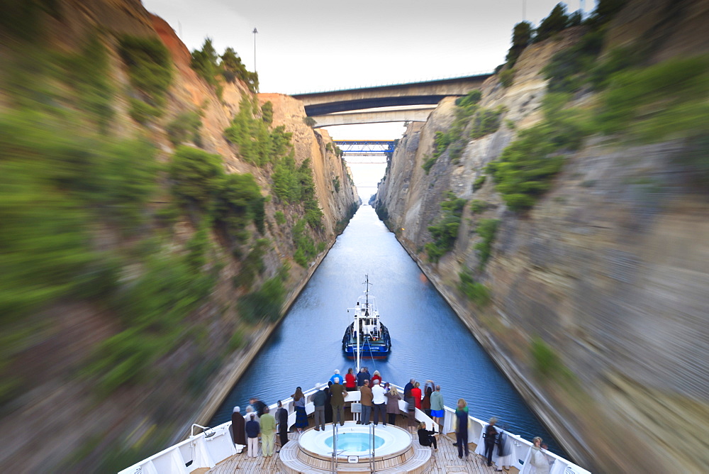 Tourists on the bow of a small cruise ship being pulled by a tug, early morning transit of Corinth Canal, Greece, Europe 