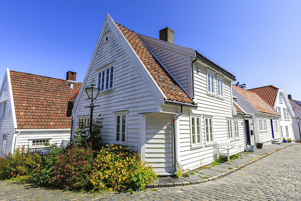 Beautiful old town, cobbled street, flowers and white wooden houses, blue sky in summer, Gamle Stavanger, Rogaland, Norway, Scandinavia, Europe