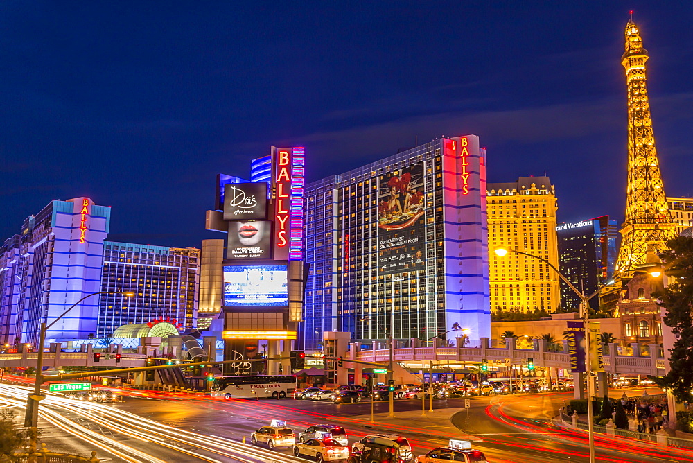 Neon lights on Las Vegas Strip at dusk with car headlights leaving streaks of light in front of Paris and Ballys, Las Vegas, Nevada, United States of America, North America 